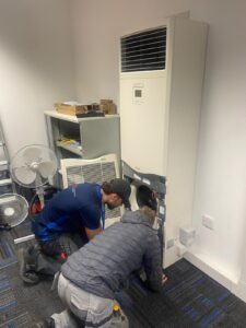 Two AKS Air Conditioning engineers inspecting and servicing a commercial indoor air conditioning unit