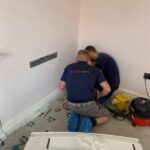 AKS engineers installing Daikin floor-standing unit with floor protection