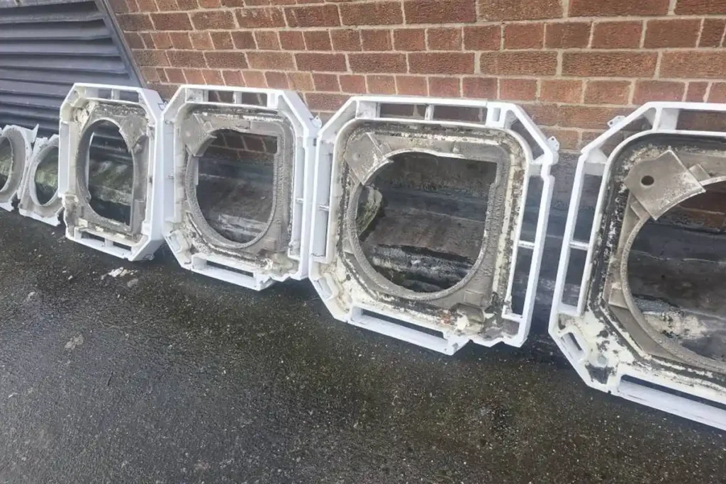 Old ceiling cassette air conditioning units stripped out and lined up outside a commercial building during a system replacement