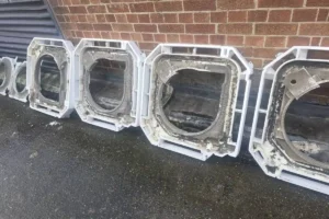 Old ceiling cassette air conditioning units stripped out and lined up outside a commercial building during a system replacement