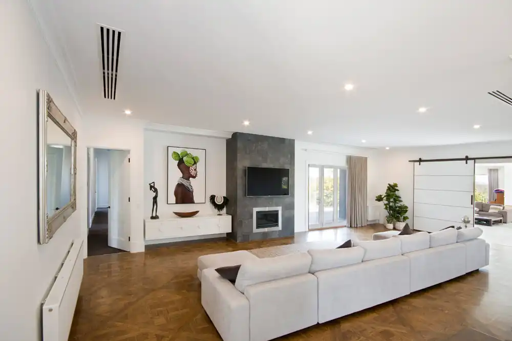 Open-plan living room in a luxury home with discreet linear slot air conditioning by AKS